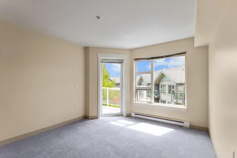 Empty carpeted room with a glass balcony door and a large window