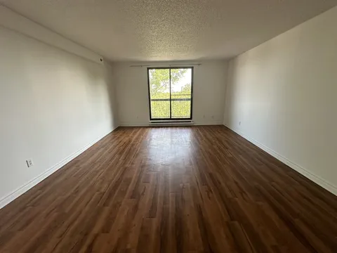 Unfurnished room with wood flooring and a window.
