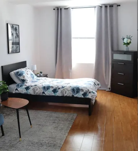 Bedroom with a floral bedspread, curtains and a window