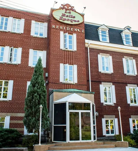 Brick building facade with white-framed windows and a glass entrance vestibule
