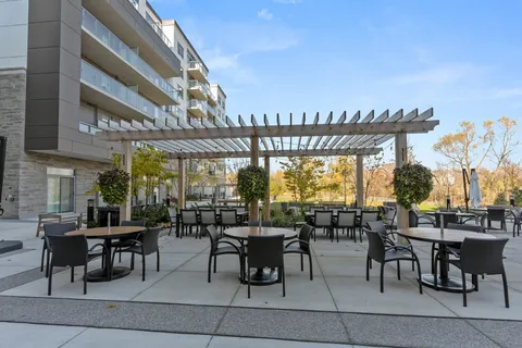 Patio tables beneath a pergola beside the residence.