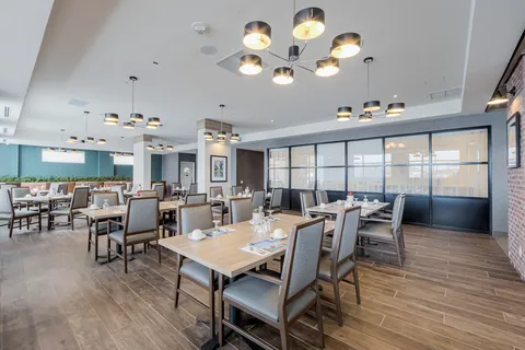 Dining room with set tables, pendant lights and large windows.
