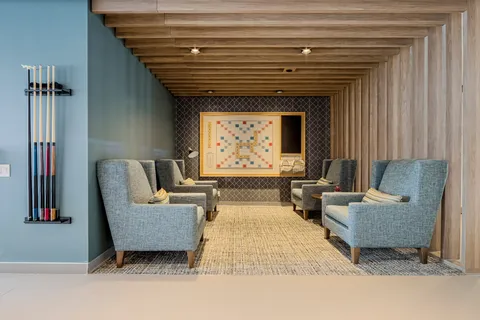 Lounge chairs beneath wood ceiling beams beside a billiards table.