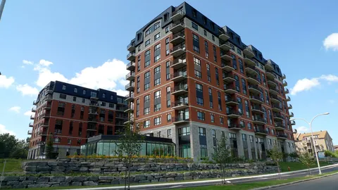 Residence towers with balconies and landscaped stone retaining walls.