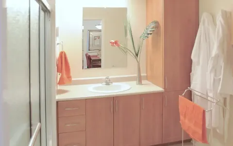 Bathroom with vanity, shower enclosure, cabinets and hanging bathrobes.