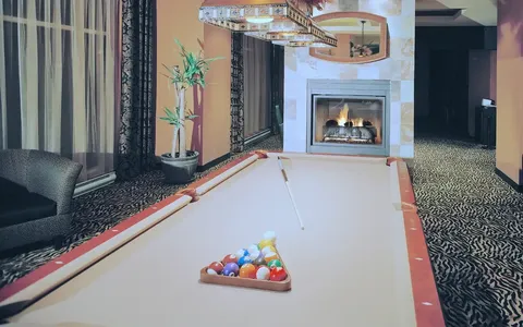 Billiards room with pool table, chairs and fireplace.