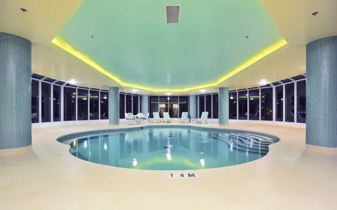 Indoor swimming pool with tiled deck and recessed ceiling lighting.