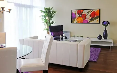 Suite living room with white sofa and purple armchair.