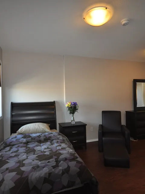 Bedroom with a single bed, bedside table, armchair and dresser.