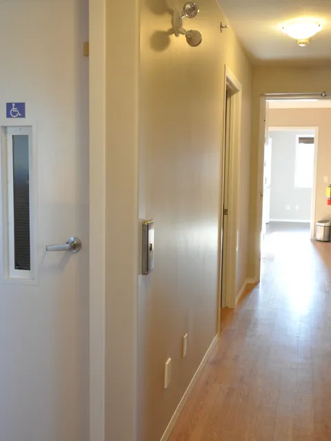 Interior corridor with wooden flooring and a wheelchair-accessible door.