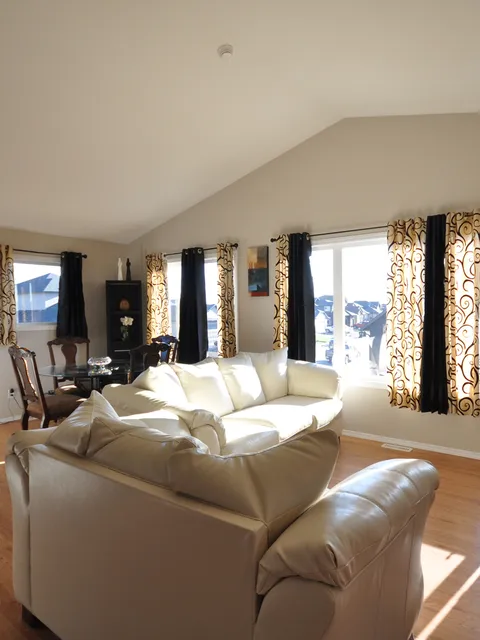 Living and dining area with cream sofas, a glass table and tall windows.