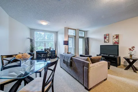 Suite living and dining area with a sofa, television and glass table.