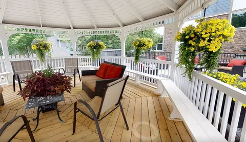 Covered patio with cushioned seating and hanging baskets.