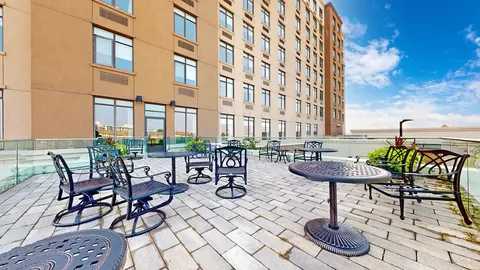 Residence building beside a paved terrace with tables and chairs