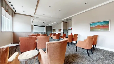 Room with orange chairs facing a blank projection screen