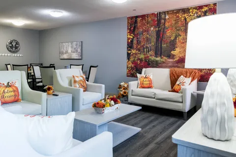 Room with pale sofas and armchairs in front of a forest mural