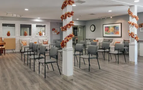 Room with rows of chairs and autumn decorations around pillars