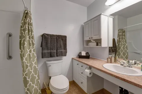 Bathroom with a toilet, sink, mirror and patterned shower curtain