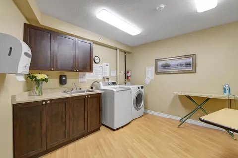 Laundry room with washing machines, cupboards, a sink and an ironing board