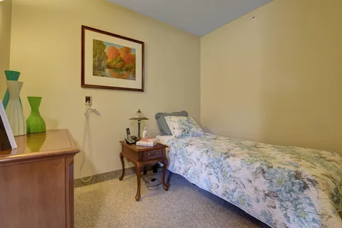 Bedroom with a single bed, floral bedding and a framed landscape picture
