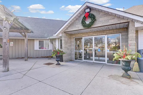 Low residence building with stone entrance, glass doors, a wreath and flower pots