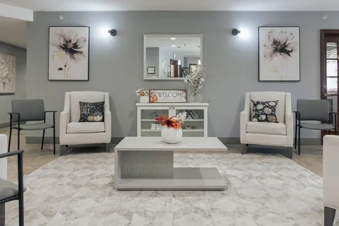 Room with pale armchairs, a coffee table, floral wall art and a mirror