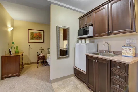 Kitchenette with brown cabinets and a sink beside a bedroom