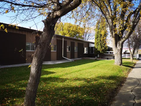Brick residence beneath autumn trees beside a paved path