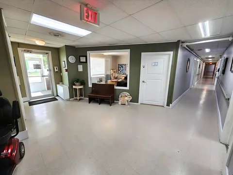 Entrance hall with a bench, office window and a long corridor