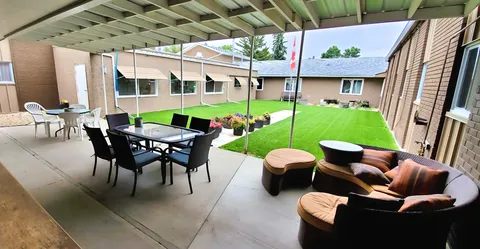 Courtyard with a lawn, covered tables and paved paths beside the building