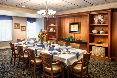 Dining table with wooden chairs, place settings and a chandelier