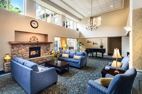 Lounge with blue seating, a stone fireplace and a grand piano