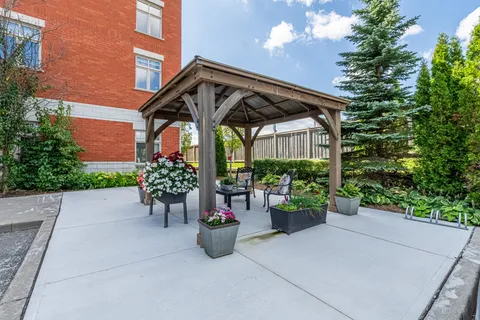 Covered patio beside the brick building with chairs and flower planters