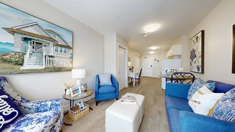 Sitting area with blue seating, a kitchenette and wall artwork