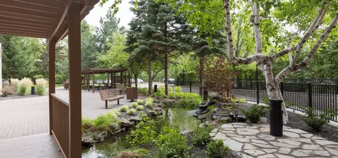 Landscaped garden with a pond, benches and a covered walkway