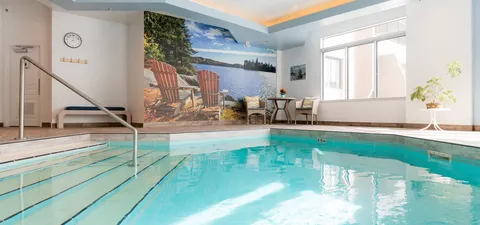 Indoor pool with steps, a handrail and a lakeside wall mural