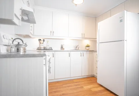 Compact white kitchen with a refrigerator, cabinets and a kettle