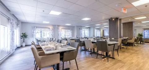 Dining room with set tables, upholstered chairs and tall windows