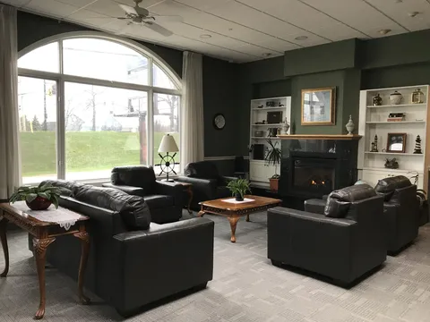 Lounge with leather seating, a fireplace, built-in shelves and a large arched window