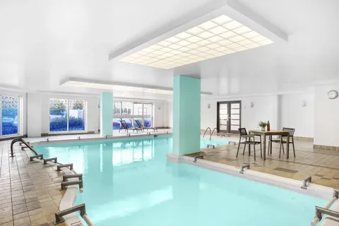 Indoor swimming pool with tiled deck, chairs and large windows