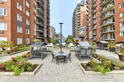 Paved courtyard with patio tables, chairs and raised planted beds