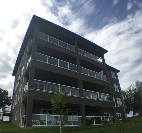Residence exterior with stacked balconies, glass railings and a lawn.