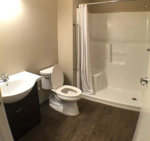 Bathroom with a sink, toilet and walk-in shower with grab rails.