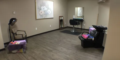 Salon with a hood dryer, wash basin, styling chair and mirrors.