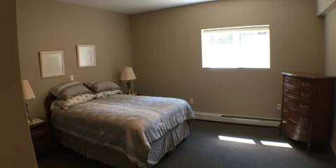 Bedroom with a double bed, bedside lamps and a chest of drawers.