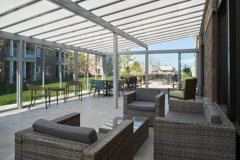 Covered patio with wicker seating and tables beside the residence