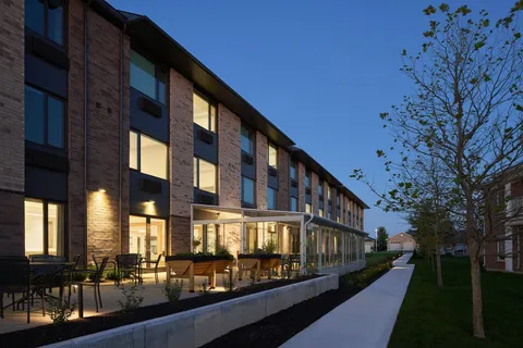 Residence building with illuminated windows beside a garden path at dusk
