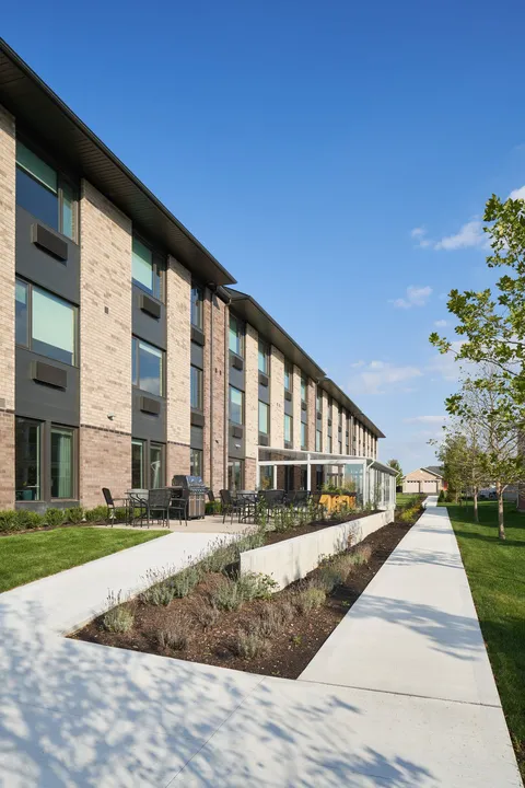Residence building beside a paved path and planted beds
