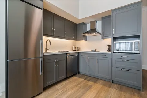 Kitchen with grey cupboards, refrigerator, cooktop and microwave