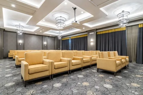 Theatre room with rows of yellow armchairs beneath chandeliers